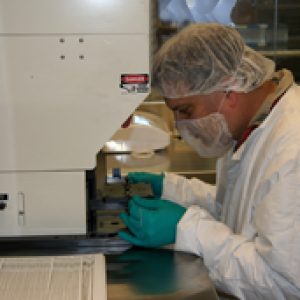Cleanroom technicians wear a variety of protective equipment including labcoats, face coverings, hairnets, and gloves.